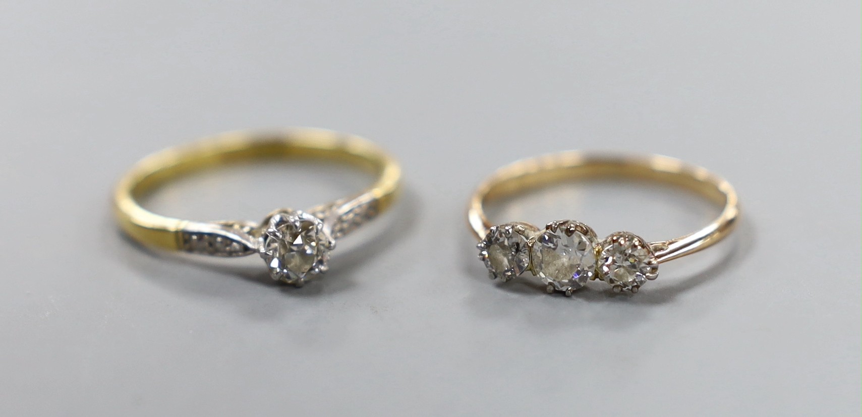 An 18ct and plat. single stone diamond ring, with diamond set shoulders, size O/P and a yellow metal and three stone diamond ring, size M, gross weight 3.8 grams.